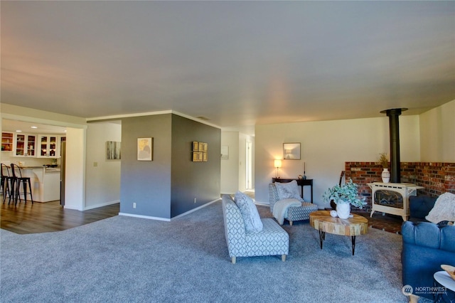 living room with carpet floors, ornamental molding, and a wood stove