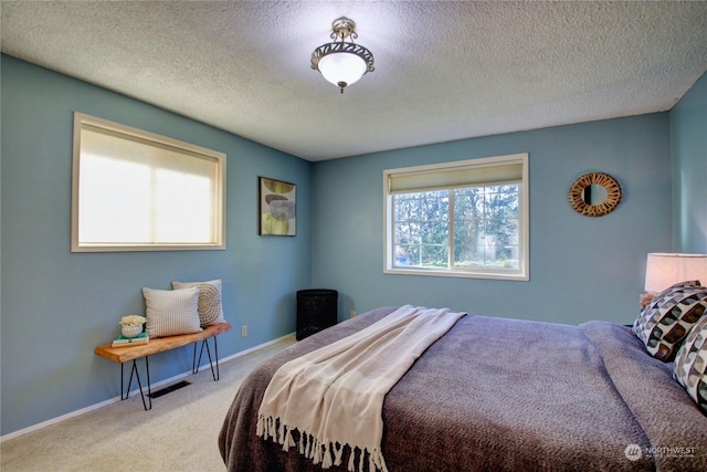 bedroom featuring light carpet and a textured ceiling