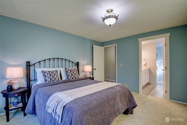 carpeted bedroom with ensuite bathroom and a textured ceiling