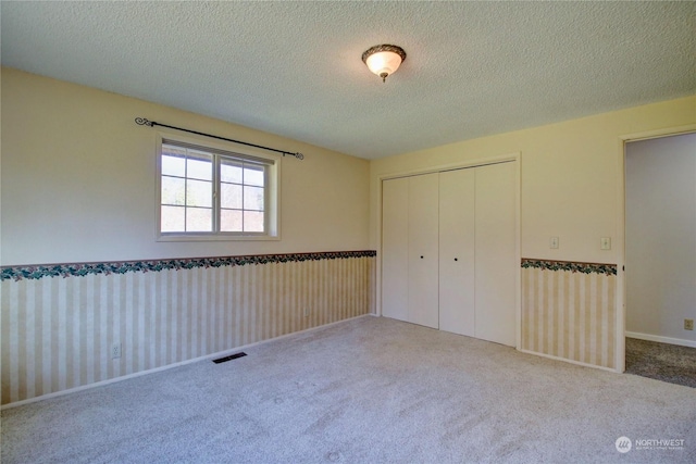 unfurnished bedroom with carpet floors, a closet, and a textured ceiling