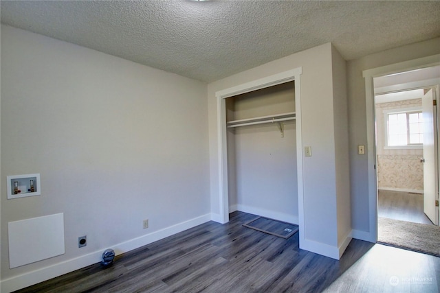 unfurnished bedroom featuring a textured ceiling, dark hardwood / wood-style flooring, and a closet