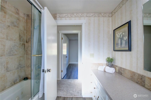 bathroom featuring hardwood / wood-style flooring, vanity, and combined bath / shower with glass door