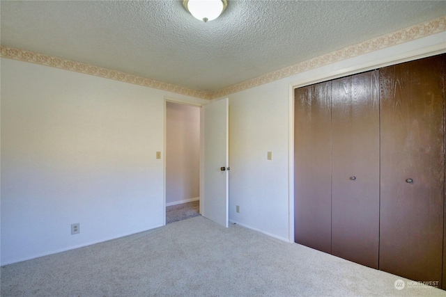 unfurnished bedroom with carpet floors, a closet, and a textured ceiling