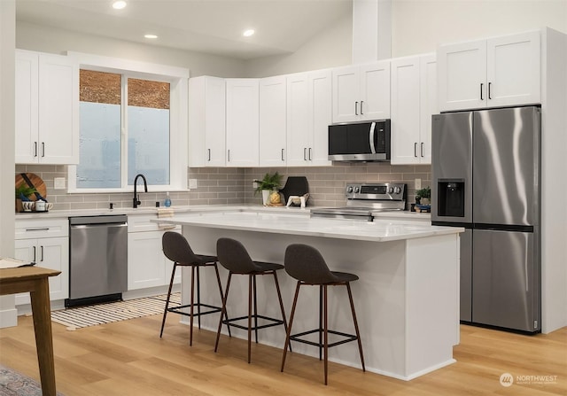 kitchen featuring appliances with stainless steel finishes, a breakfast bar, light wood-style flooring, and white cabinets