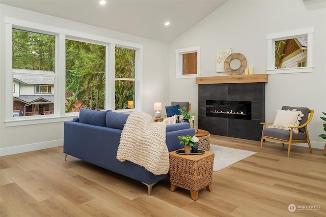 living room featuring lofted ceiling, a fireplace, and light wood-type flooring