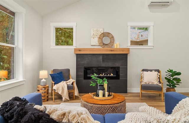 living room with vaulted ceiling, hardwood / wood-style floors, and an AC wall unit