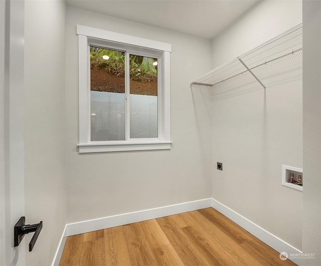 clothes washing area with wood-type flooring, hookup for an electric dryer, and hookup for a washing machine