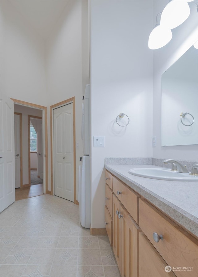 bathroom featuring tile patterned flooring, vanity, and a towering ceiling