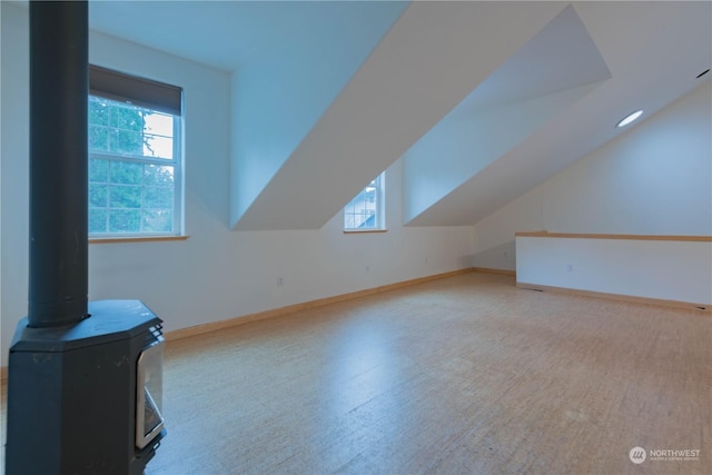 bonus room with lofted ceiling and a wood stove