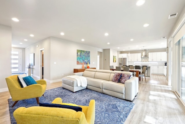 living room featuring light wood-style flooring, visible vents, baseboards, and recessed lighting