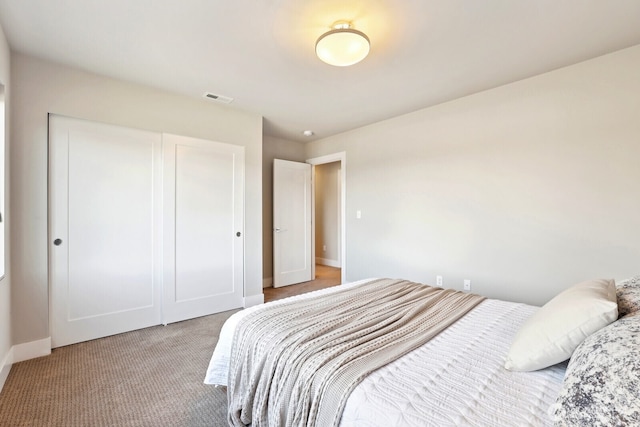 bedroom featuring a closet, carpet flooring, visible vents, and baseboards