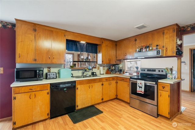 kitchen with appliances with stainless steel finishes, sink, and light wood-type flooring