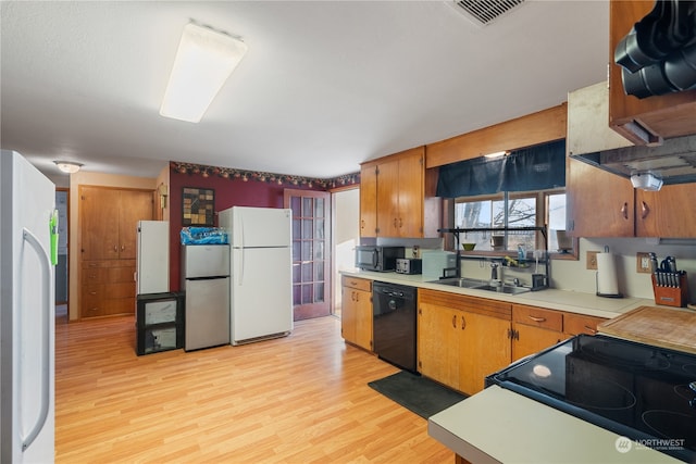 kitchen featuring sink, light hardwood / wood-style flooring, and black appliances