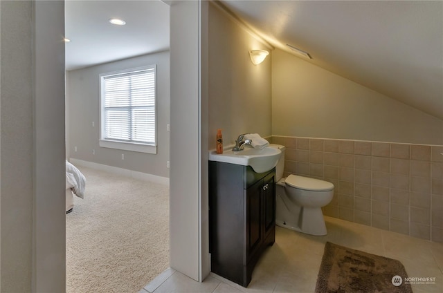 bathroom with vaulted ceiling, tile walls, vanity, toilet, and tile patterned floors