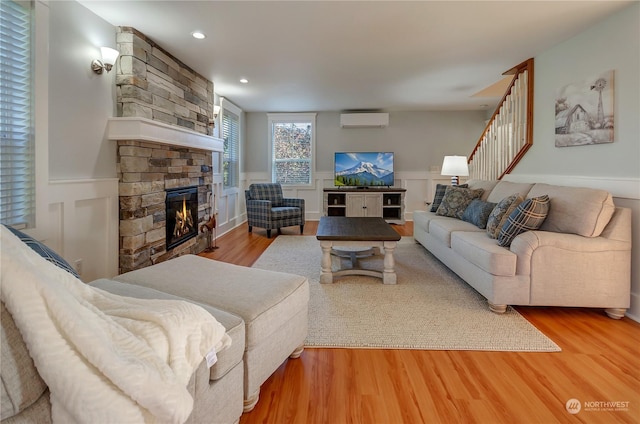 living room featuring wood-type flooring, a fireplace, and a wall mounted AC