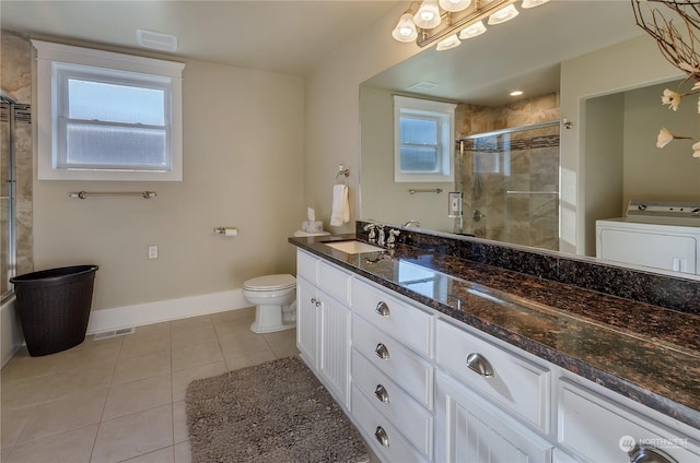 bathroom with tile patterned flooring, vanity, washer / dryer, and a healthy amount of sunlight