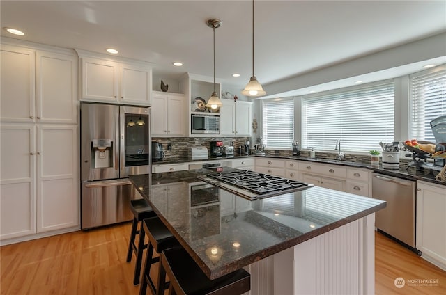 kitchen featuring pendant lighting, sink, appliances with stainless steel finishes, a center island, and white cabinets