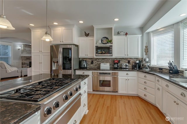 kitchen with white cabinetry, appliances with stainless steel finishes, and decorative light fixtures