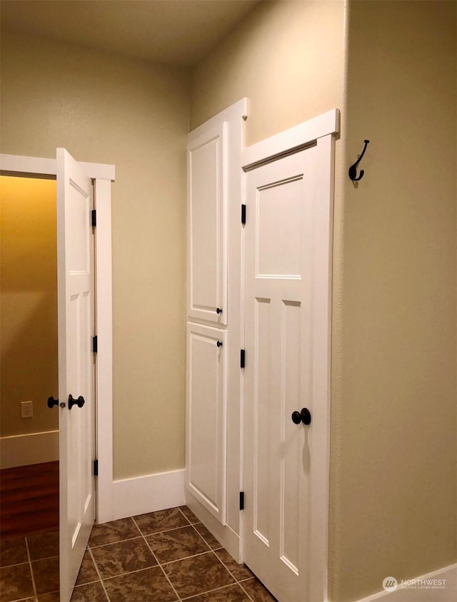 hallway featuring dark tile patterned floors