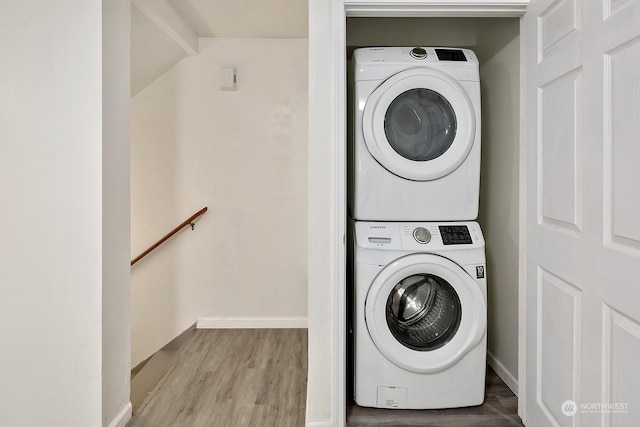 clothes washing area featuring stacked washer and clothes dryer and light hardwood / wood-style floors