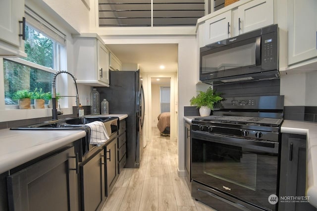 kitchen with white cabinetry, light hardwood / wood-style flooring, decorative backsplash, and black appliances