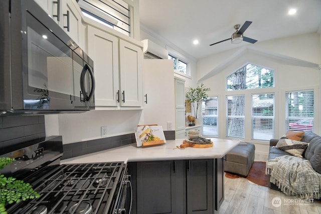 kitchen with black appliances, a wall unit AC, ceiling fan, light hardwood / wood-style floors, and white cabinets