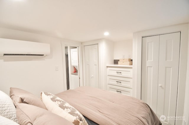 bedroom with a wall mounted air conditioner and multiple closets