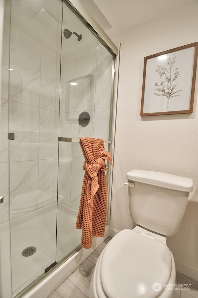 bathroom featuring toilet and a shower with shower door