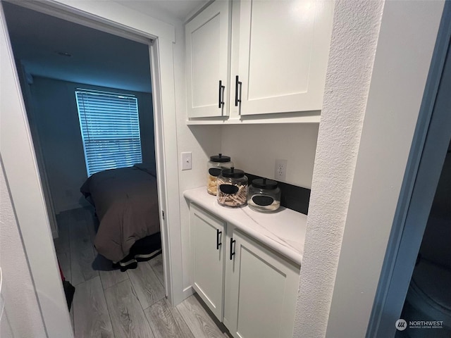 bar featuring white cabinetry and light hardwood / wood-style floors