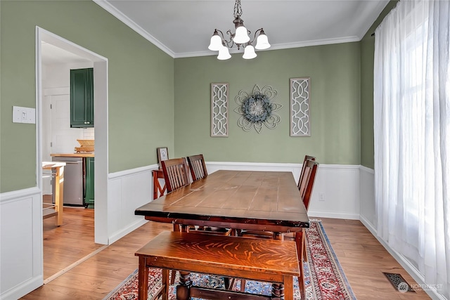 dining space featuring light hardwood / wood-style flooring, ornamental molding, and a chandelier