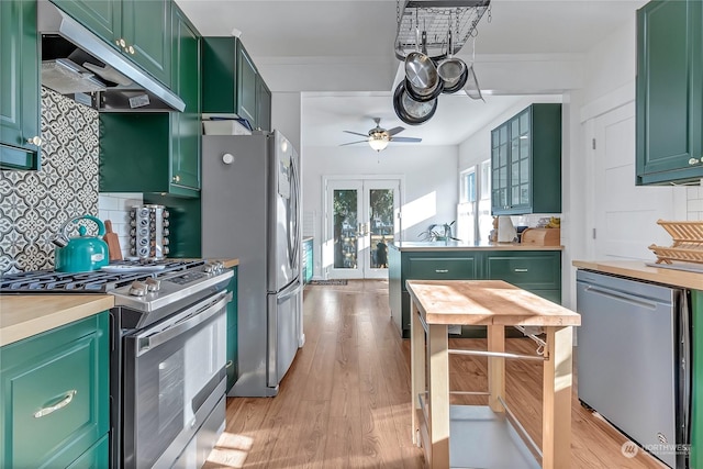 kitchen featuring range hood, stainless steel appliances, light hardwood / wood-style floors, and green cabinets