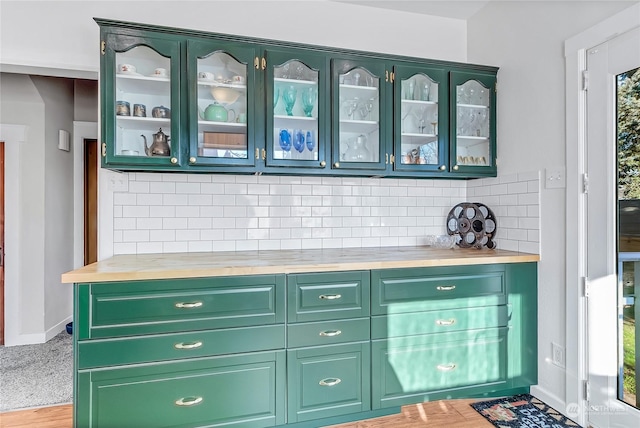 bar with butcher block countertops, backsplash, light hardwood / wood-style flooring, and green cabinetry