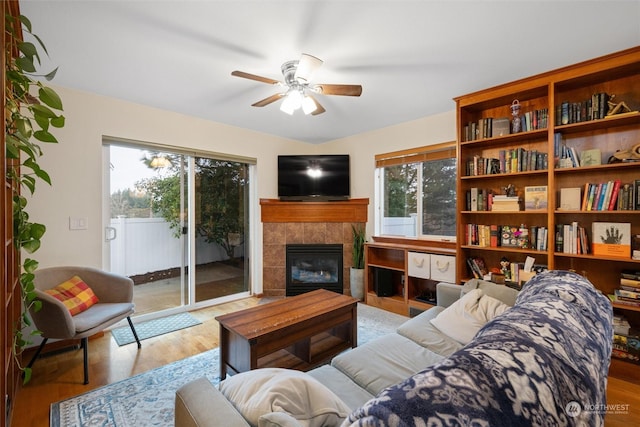 living room featuring ceiling fan, a tile fireplace, and light hardwood / wood-style flooring