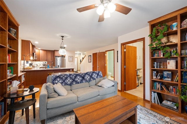 living room featuring ceiling fan, sink, and light wood-type flooring