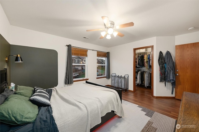 bedroom with hardwood / wood-style flooring, a spacious closet, ceiling fan, and a closet