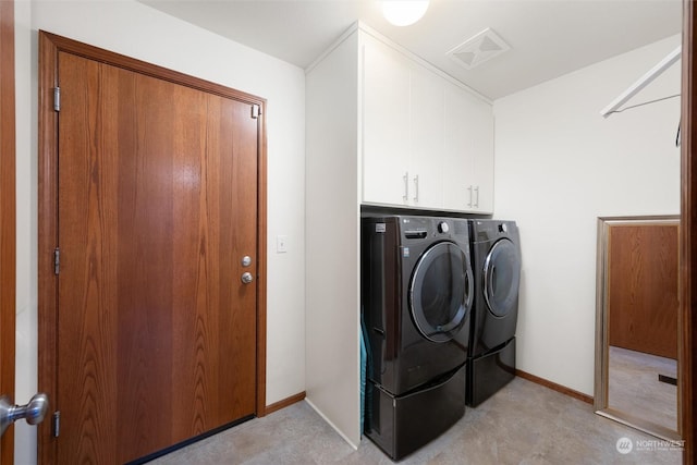 clothes washing area with washer and clothes dryer and cabinets