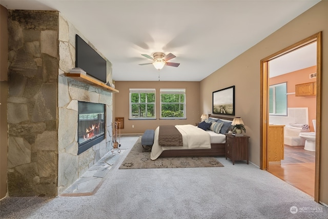 carpeted bedroom featuring ensuite bathroom, a fireplace, and ceiling fan