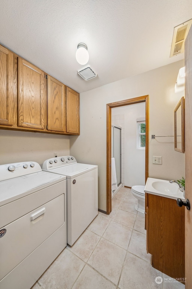 washroom with light tile patterned flooring, sink, a textured ceiling, and independent washer and dryer