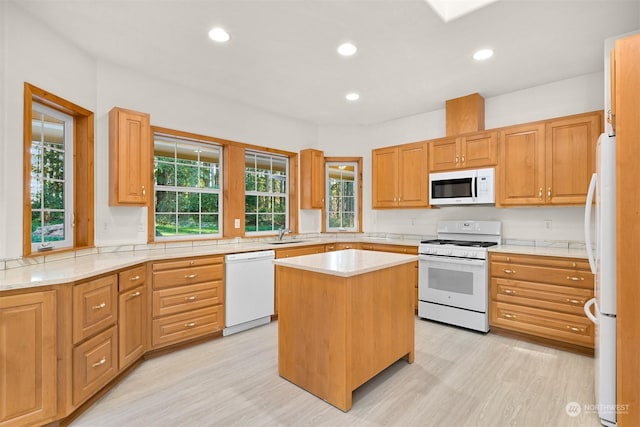 kitchen with white appliances, sink, a center island, and light hardwood / wood-style floors