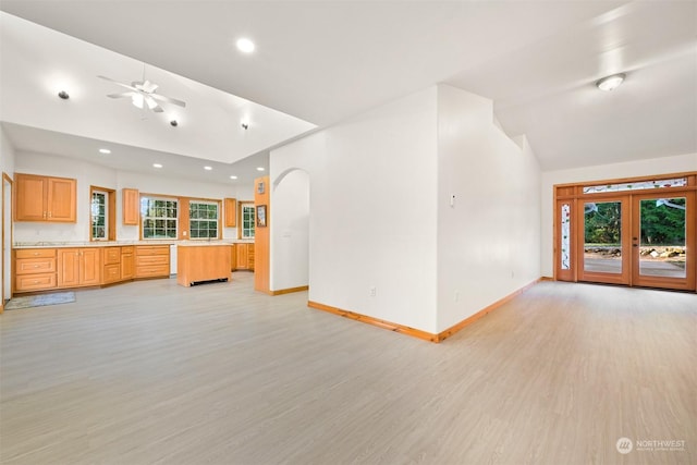 unfurnished living room featuring lofted ceiling, light hardwood / wood-style flooring, french doors, and ceiling fan