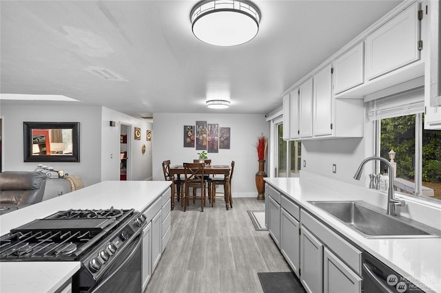 kitchen featuring sink, gas stove, white cabinetry, dishwasher, and light hardwood / wood-style floors