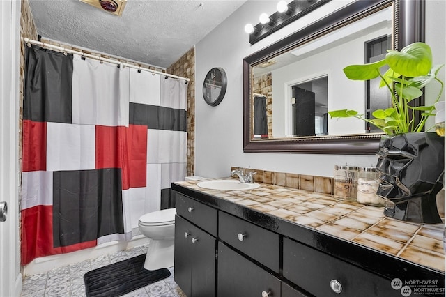 bathroom with vanity, toilet, and a textured ceiling