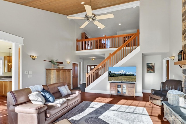 living room with wood ceiling, hardwood / wood-style flooring, ceiling fan, and a high ceiling