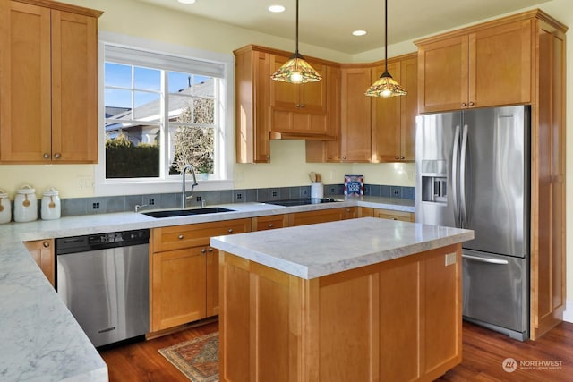 kitchen featuring dark wood-type flooring, sink, decorative light fixtures, a center island, and appliances with stainless steel finishes