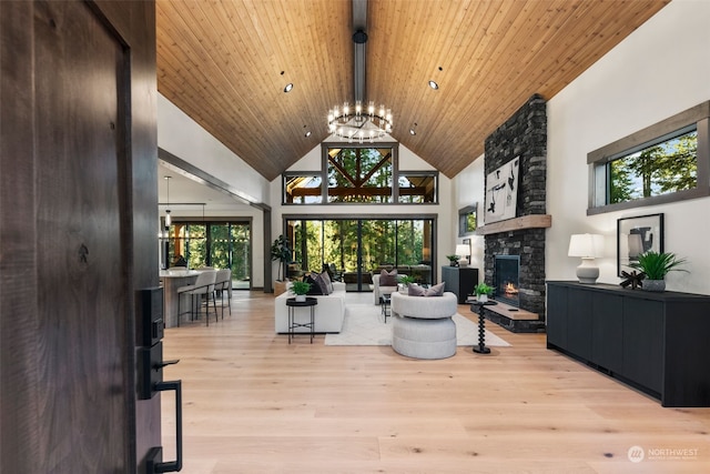 living room featuring a wealth of natural light, a notable chandelier, high vaulted ceiling, and light hardwood / wood-style floors