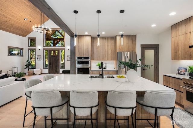 kitchen with a large island, sink, decorative light fixtures, and appliances with stainless steel finishes