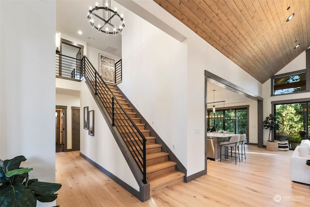 stairway with high vaulted ceiling, a chandelier, hardwood / wood-style floors, and wooden ceiling