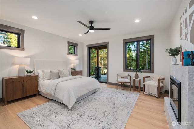 bedroom with a fireplace, access to outside, light hardwood / wood-style floors, and ceiling fan