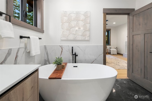 bathroom featuring vanity, tile walls, and a bathtub