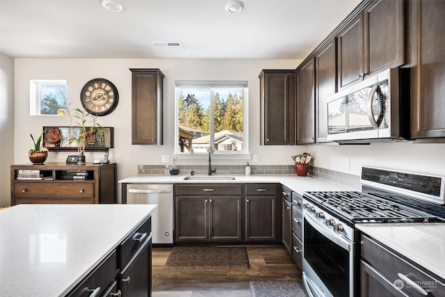 kitchen with stainless steel appliances, dark brown cabinets, sink, and dark wood-type flooring